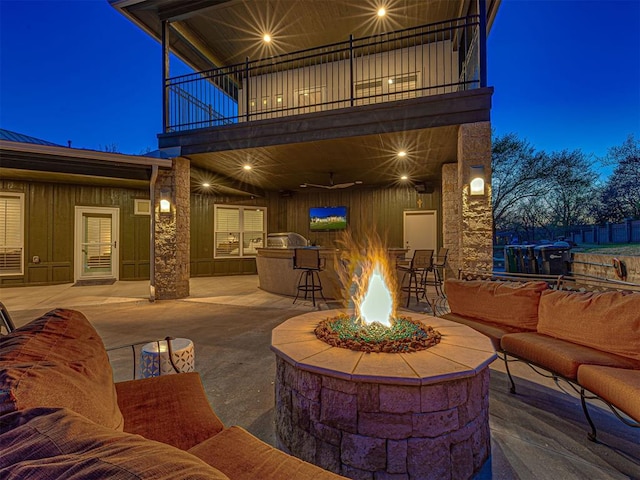 view of patio with a balcony and an outdoor living space with a fire pit