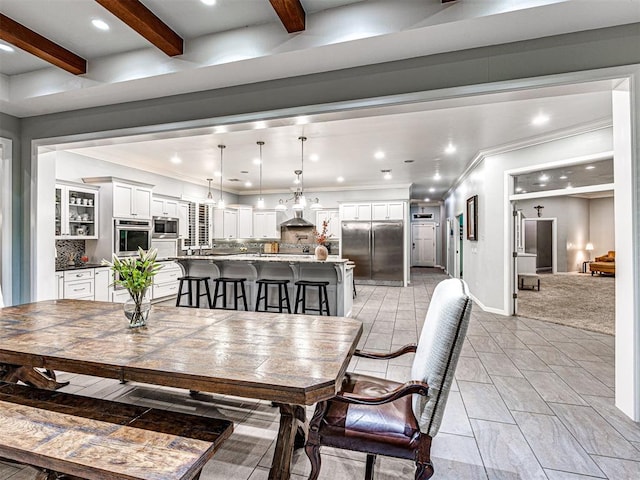 carpeted dining room with beamed ceiling and ornamental molding