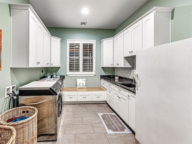 kitchen featuring tasteful backsplash, sink, washer and dryer, white cabinets, and butcher block countertops