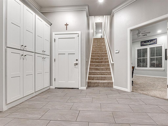 carpeted foyer entrance featuring ceiling fan and crown molding