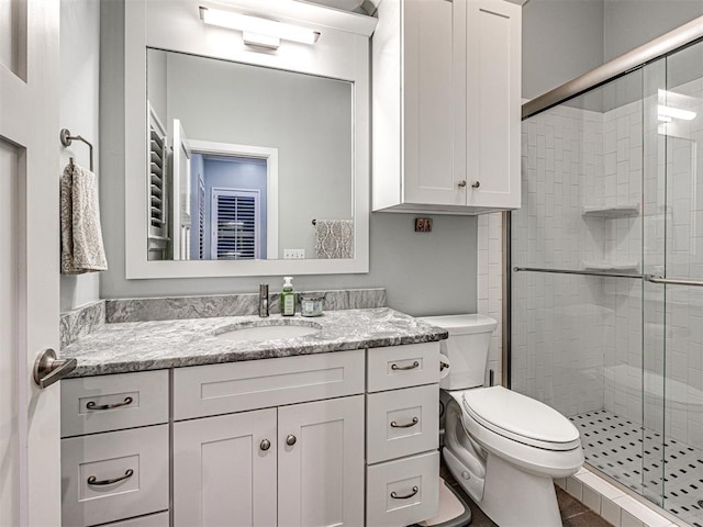 bathroom featuring tile patterned floors, vanity, a shower with shower door, and toilet