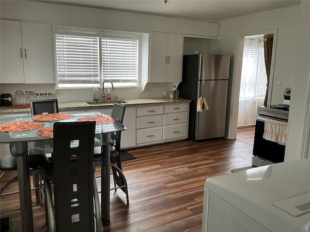 kitchen featuring white cabinetry, stainless steel fridge, sink, and electric range oven