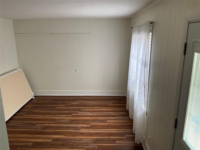 empty room with dark hardwood / wood-style flooring and wooden walls