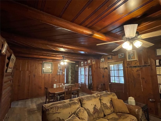 living room with beam ceiling, wood walls, ceiling fan, and wood ceiling