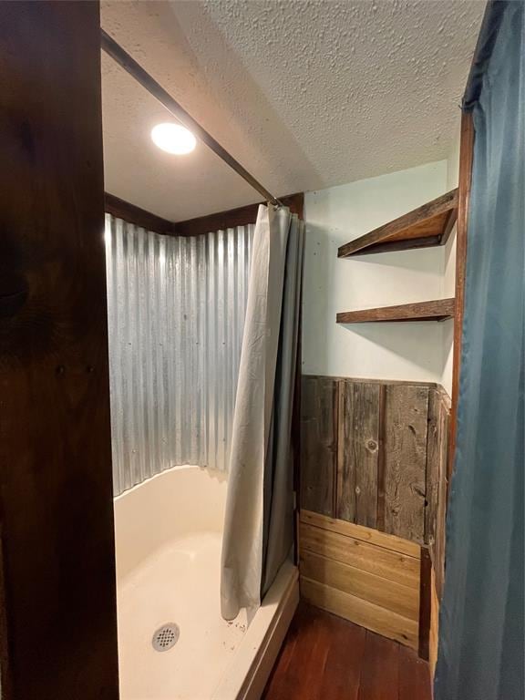 bathroom with hardwood / wood-style floors, a textured ceiling, and walk in shower