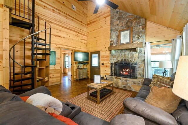 living room featuring a healthy amount of sunlight, a stone fireplace, dark wood-type flooring, and high vaulted ceiling