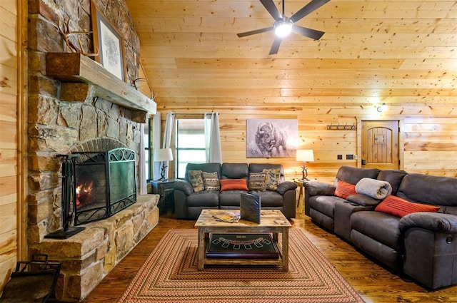 living room with ceiling fan, hardwood / wood-style flooring, a fireplace, a high ceiling, and wood walls