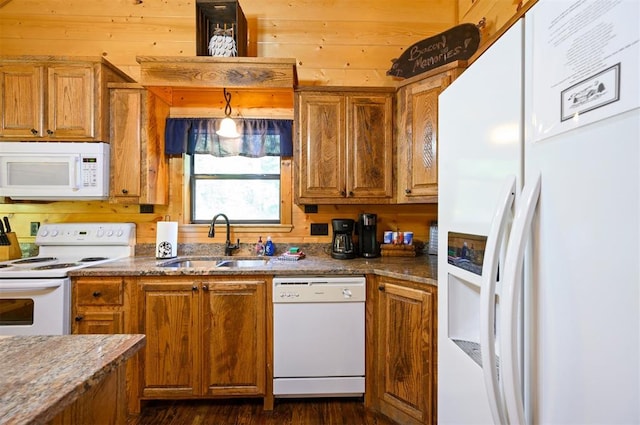 kitchen with white appliances, sink, dark stone countertops, dark hardwood / wood-style floors, and hanging light fixtures