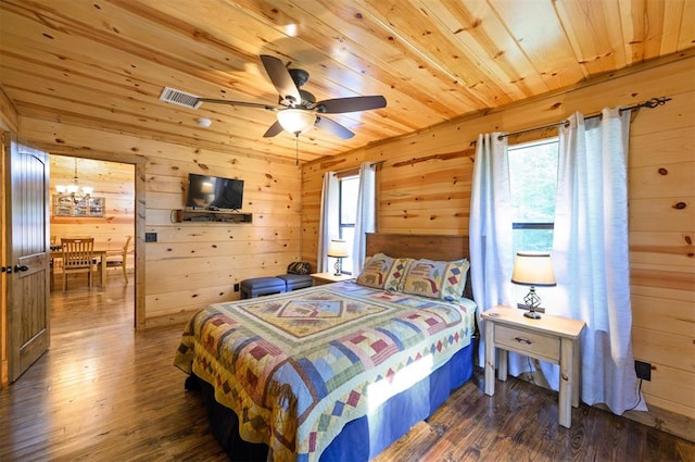 bedroom featuring ceiling fan with notable chandelier, dark wood-type flooring, and wood walls