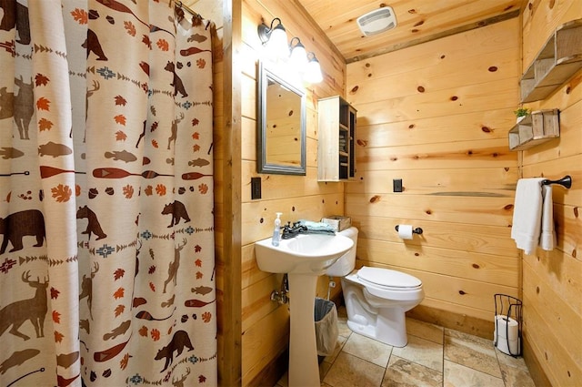 bathroom with a shower with curtain, toilet, wood ceiling, and wood walls