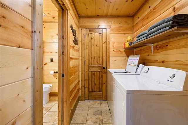 clothes washing area with washing machine and dryer, wooden ceiling, and wooden walls