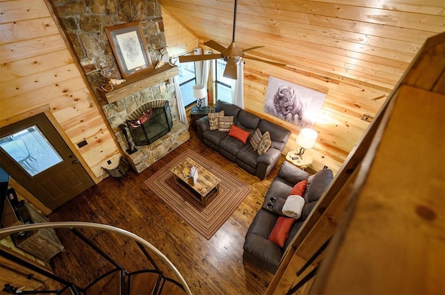 living room featuring wood walls, vaulted ceiling, hardwood / wood-style flooring, ceiling fan, and a fireplace