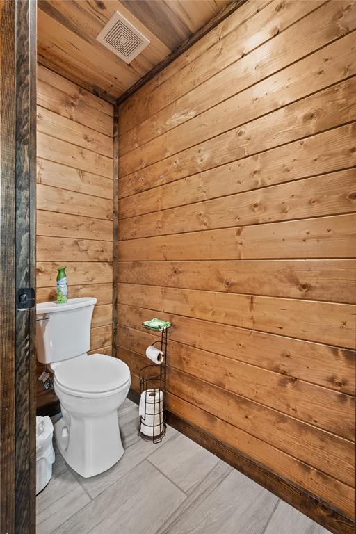 bathroom with toilet, wooden ceiling, and wooden walls