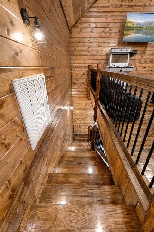 stairway with hardwood / wood-style flooring, vaulted ceiling, and wooden walls