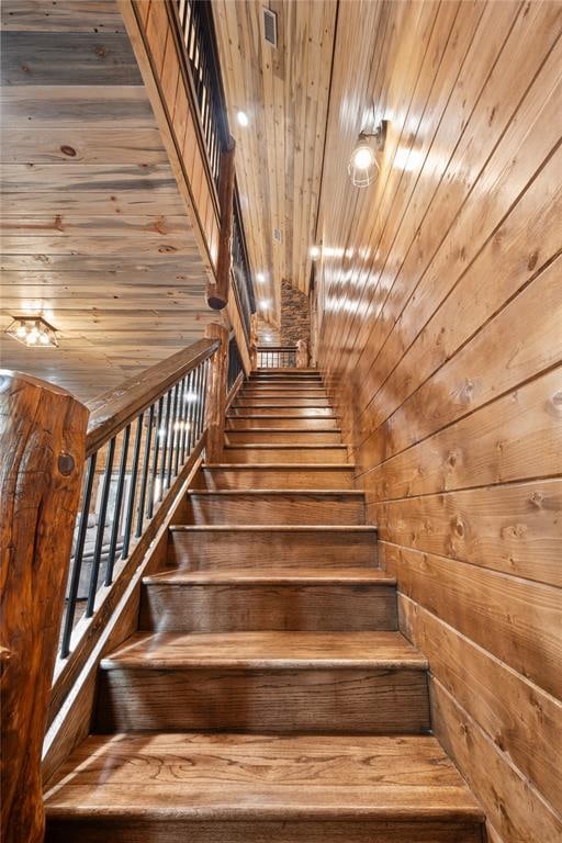 staircase with wood walls, wooden ceiling, and wood-type flooring