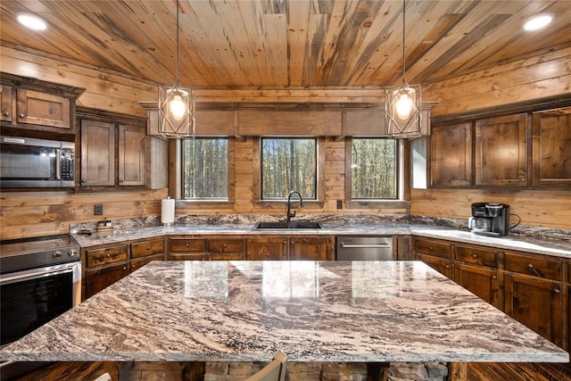 kitchen with sink, a kitchen island, dark stone counters, and appliances with stainless steel finishes