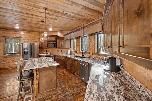 kitchen featuring stone counters, decorative light fixtures, a kitchen island, dark hardwood / wood-style flooring, and stainless steel appliances