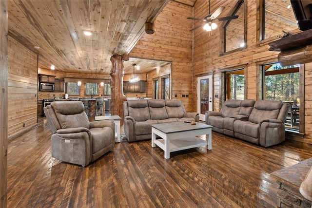 living room with high vaulted ceiling, wooden walls, dark hardwood / wood-style floors, ceiling fan, and wood ceiling