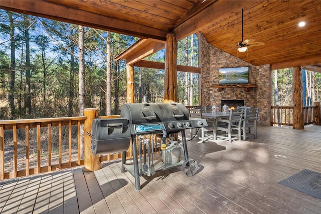 wooden deck with ceiling fan and an outdoor stone fireplace