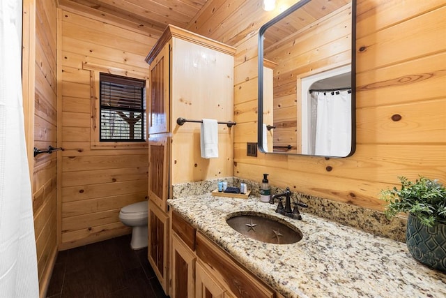 bathroom featuring wooden walls, vanity, wooden ceiling, and toilet