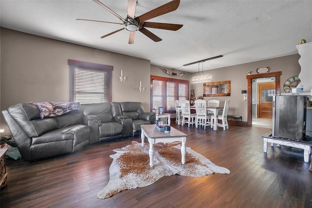 living room featuring a textured ceiling, ceiling fan, and dark wood-type flooring