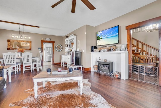 living room featuring ceiling fan with notable chandelier, dark hardwood / wood-style floors, and a wood stove