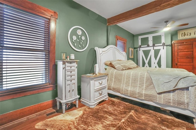 bedroom with beam ceiling, a barn door, ceiling fan, and wood-type flooring