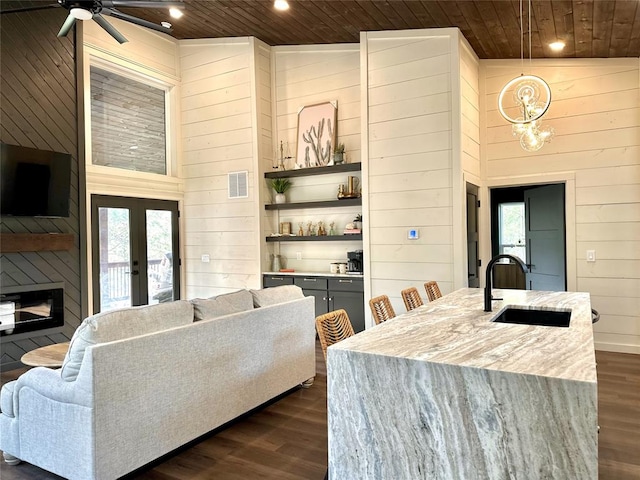 living room with dark hardwood / wood-style floors, wood walls, wood ceiling, and sink