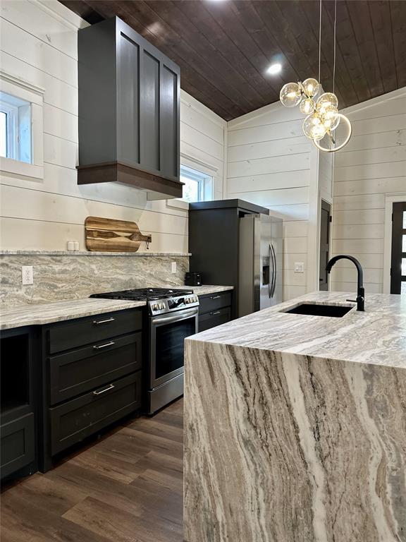 kitchen with wood walls, wood ceiling, stainless steel appliances, and vaulted ceiling