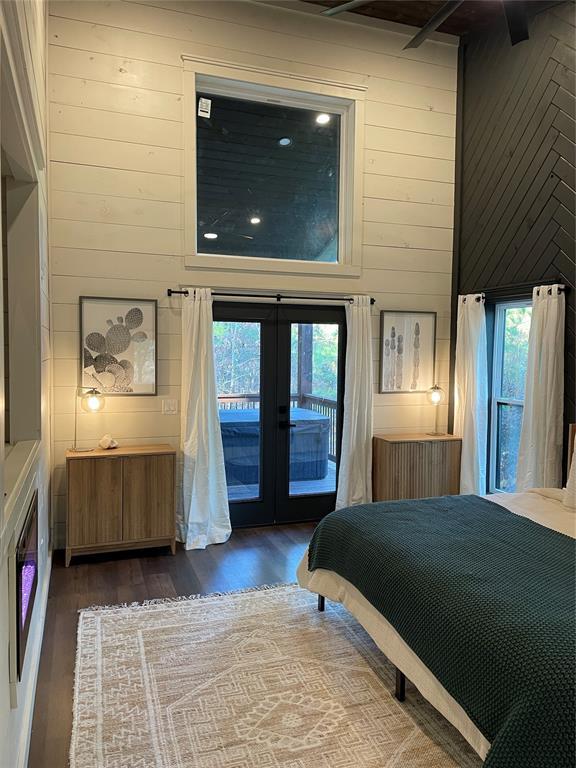 bedroom with dark hardwood / wood-style flooring, access to exterior, multiple windows, and french doors