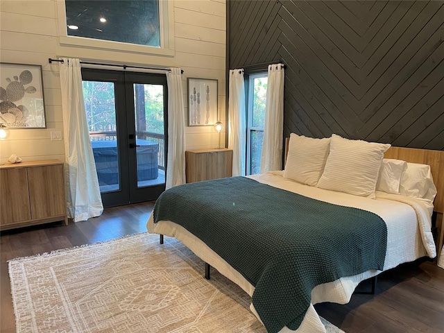 bedroom featuring wood walls, multiple windows, access to outside, and french doors