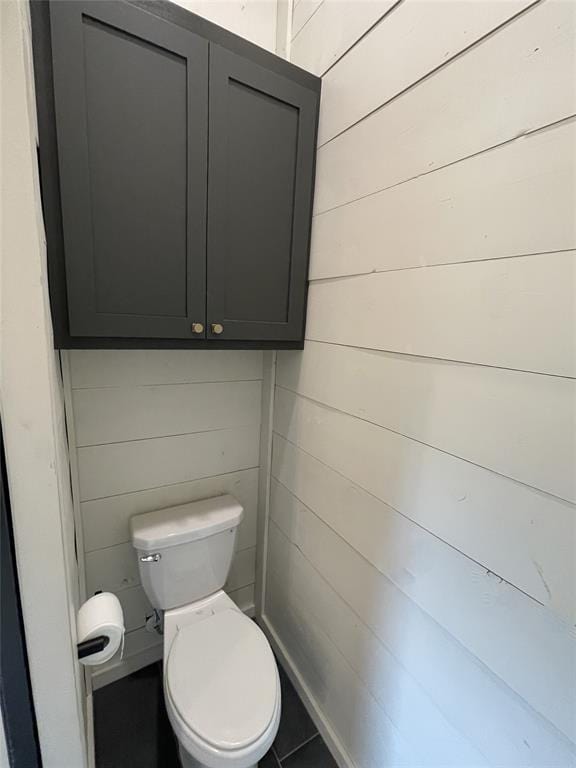 bathroom featuring toilet and wood walls