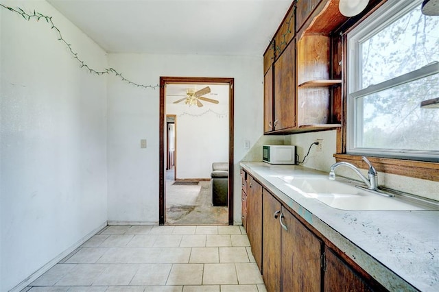 kitchen with light tile patterned flooring, ceiling fan, and sink