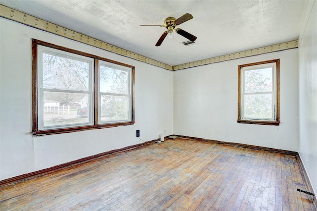 unfurnished room with ceiling fan, a healthy amount of sunlight, a textured ceiling, and light hardwood / wood-style flooring