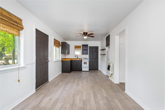 kitchen with white range, heating unit, sink, light hardwood / wood-style flooring, and butcher block countertops