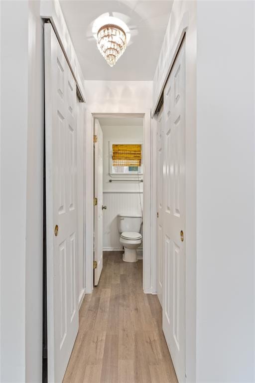 hall with an inviting chandelier and light hardwood / wood-style flooring