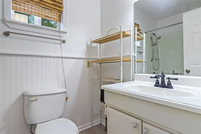 bathroom featuring hardwood / wood-style flooring, toilet, vanity, and walk in shower