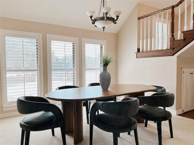 carpeted dining space with plenty of natural light, lofted ceiling, and a notable chandelier