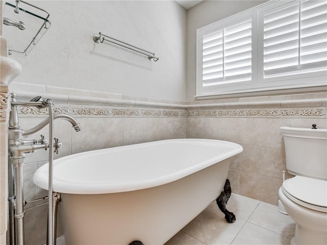 bathroom featuring toilet, tile patterned floors, tile walls, and a tub