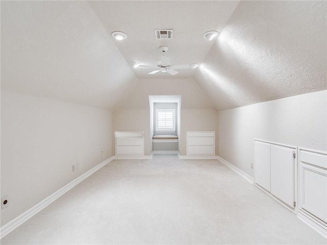 bonus room featuring a textured ceiling, light colored carpet, ceiling fan, and lofted ceiling