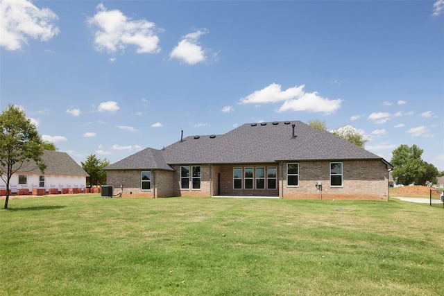 rear view of property with a yard and central air condition unit