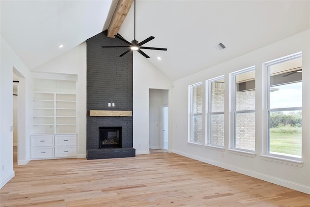 unfurnished living room featuring beam ceiling, light wood-type flooring, and a brick fireplace