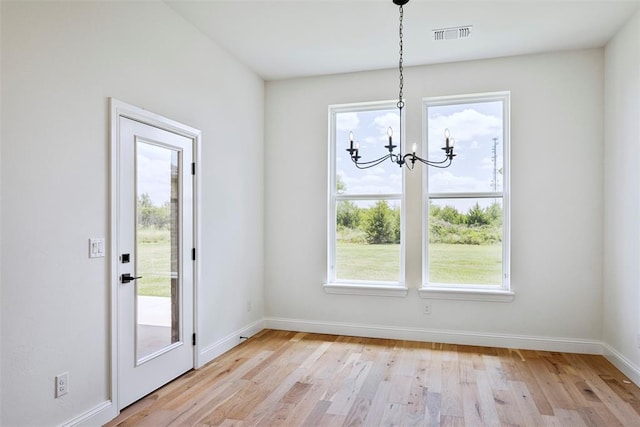 unfurnished dining area featuring plenty of natural light, a chandelier, and light wood-type flooring