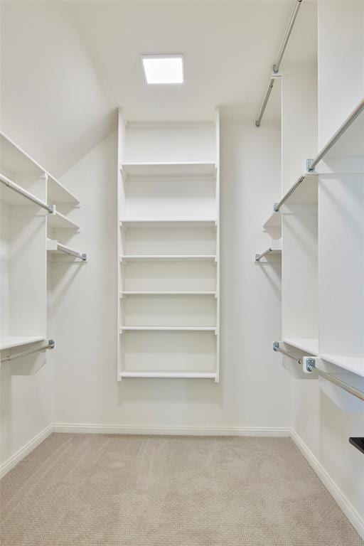 walk in closet with light colored carpet and lofted ceiling