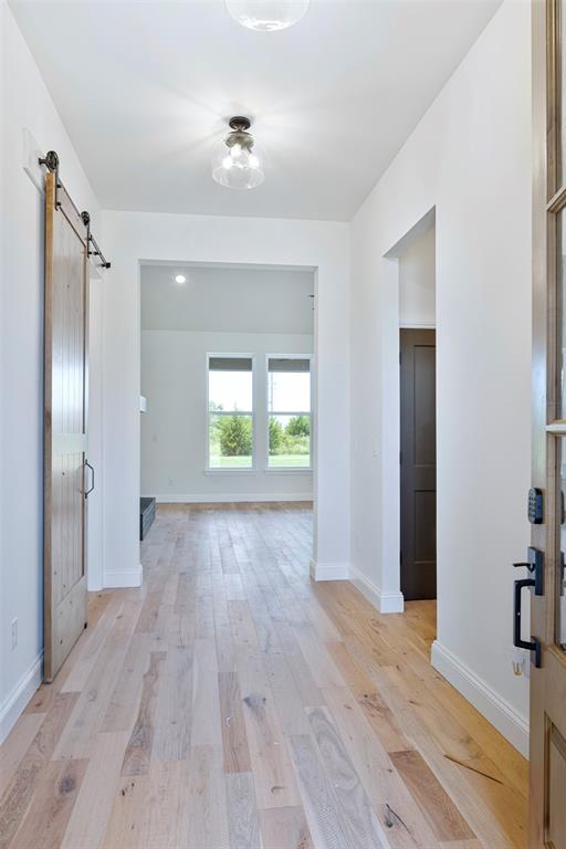 corridor featuring a barn door and light wood-type flooring