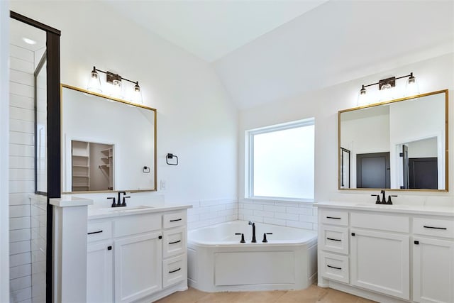 bathroom featuring tile patterned floors, vanity, a bathing tub, and lofted ceiling