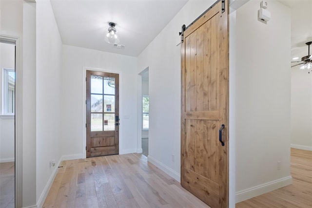 foyer featuring a barn door, light hardwood / wood-style flooring, and ceiling fan