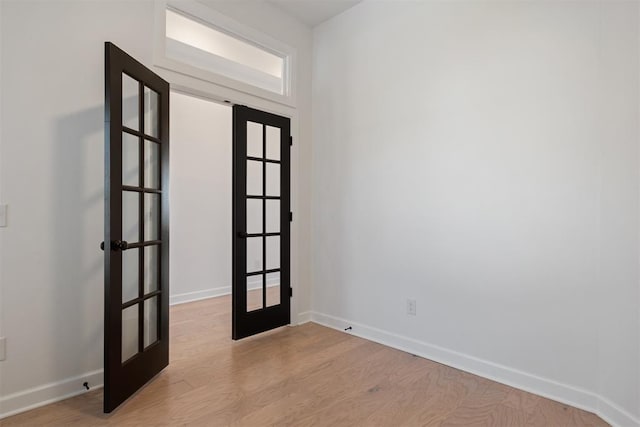 spare room featuring french doors and light wood-type flooring