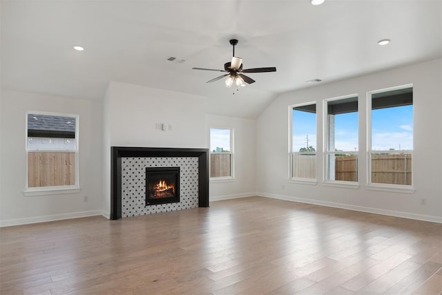 unfurnished living room with ceiling fan, light hardwood / wood-style floors, lofted ceiling, and a tile fireplace