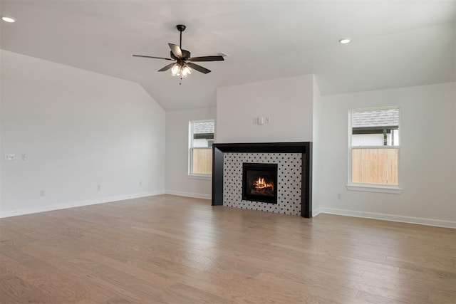 unfurnished living room featuring a tile fireplace, a healthy amount of sunlight, and light hardwood / wood-style floors